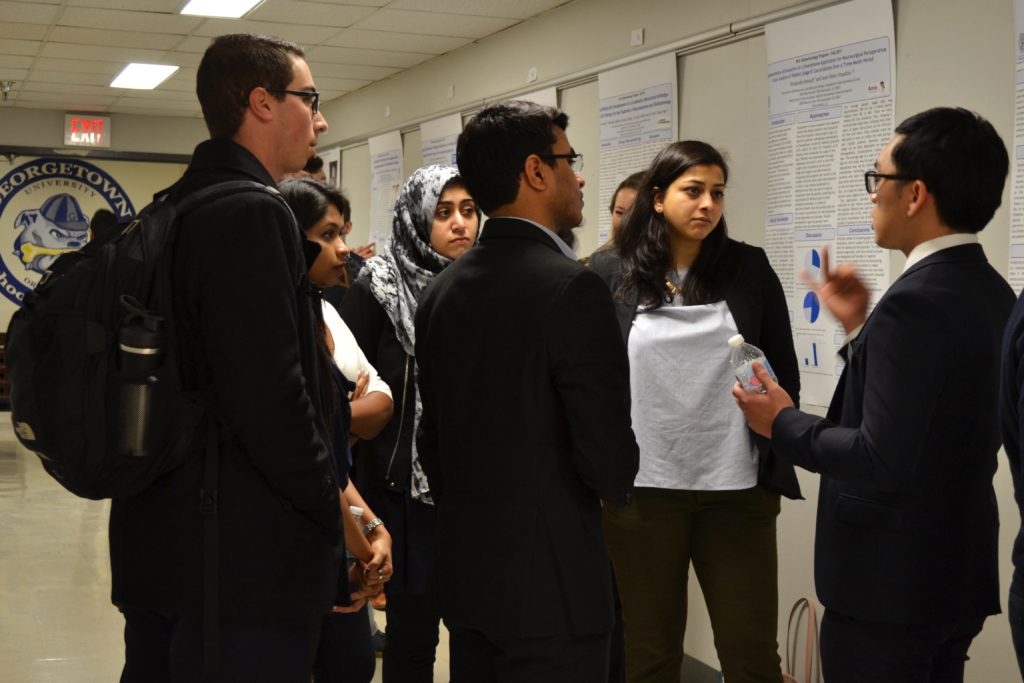 A biotechnology student explaining his internship research to a group of peers and faculty
